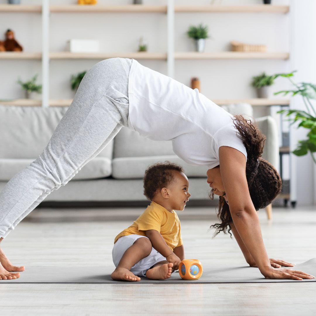 mom doing yoga with her baby playing below her