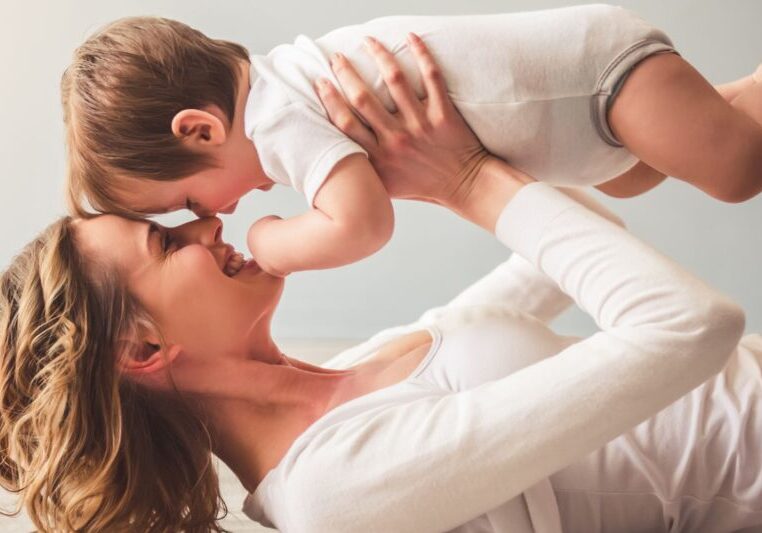 A mother laying down holding her baby above her